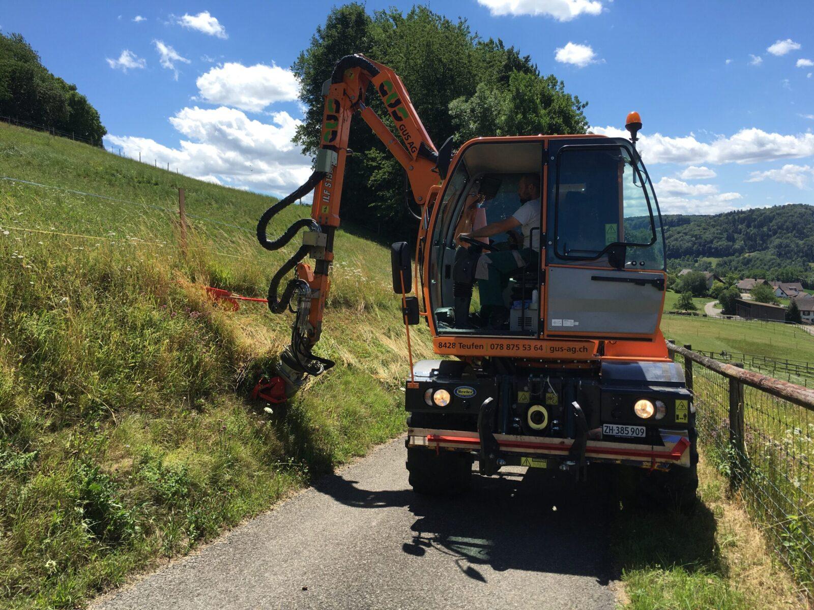 Energreen mit Messerbalken beim Böschungsunterhalt, schneidet das Gras an einem Fuss- und Radweg.