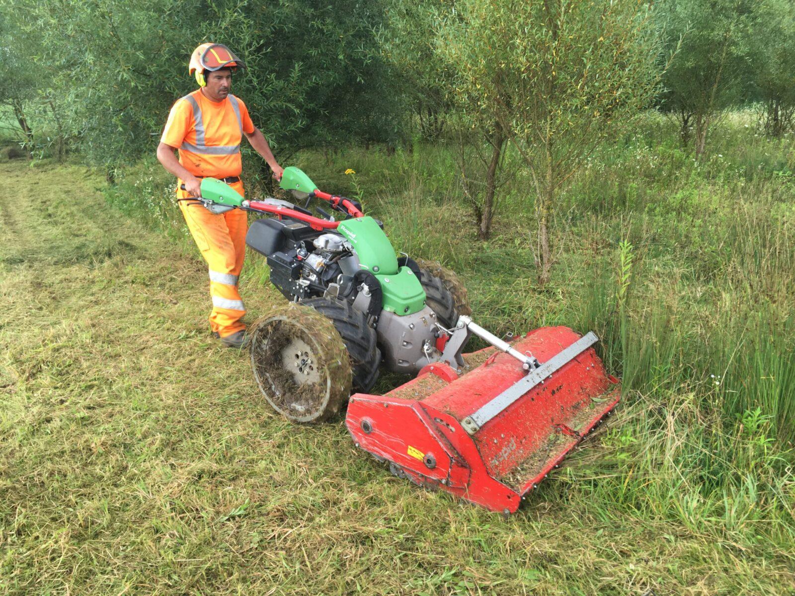 Ein Mitarbeiter arbeitet von Hand mit dem Rapid Flächenmulcher an einer Stelle, wo kein grosser Traktor-Mulcher hin kann.